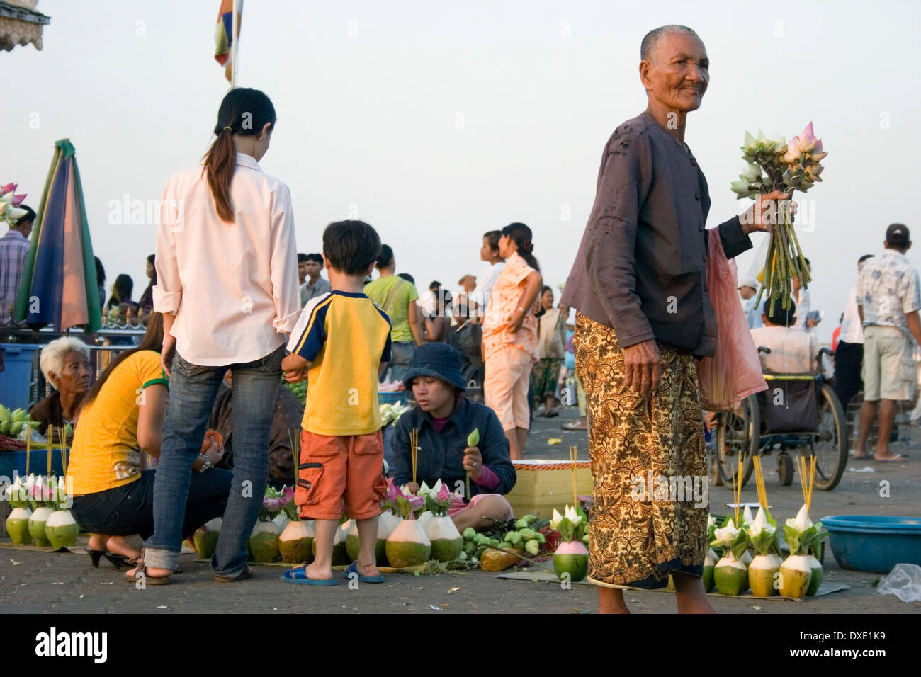 Un anziano laica buddista che trasportano fiori è passato a piedi fiore femmina fornitori in Phnom Penh Cambogia. Foto Stock