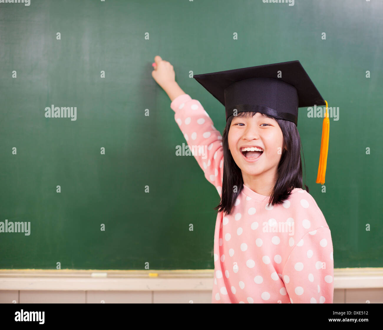 Felice bambina indossa un cappello di laurea con Blackboard Foto Stock
