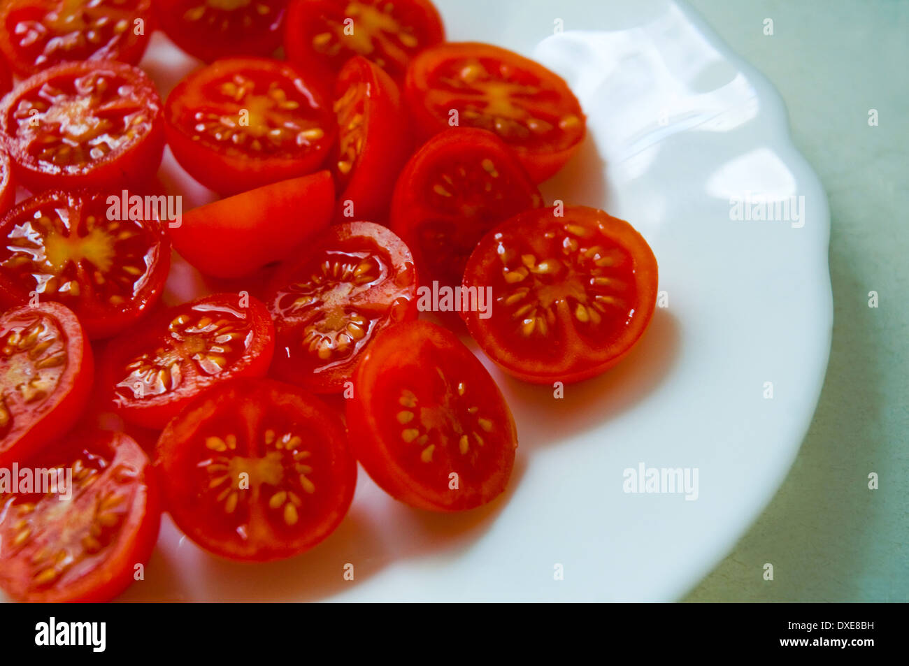 Pomodori ciliegia su una piastra, tagliato in due metà. Chiudere la vista. Foto Stock