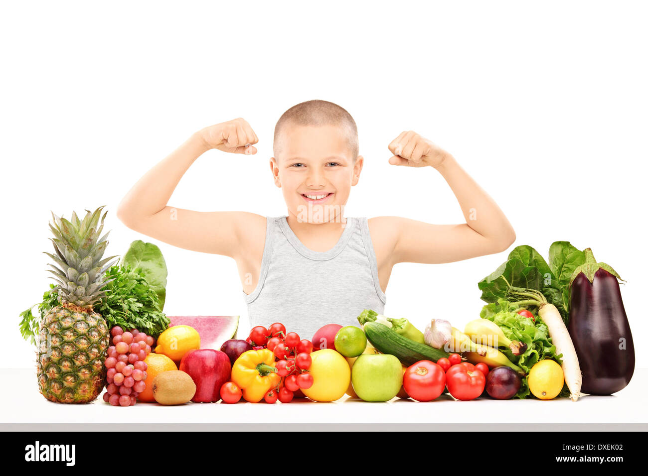 Ragazzo che mostra i muscoli dietro il mucchio di frutta e verdura Foto Stock