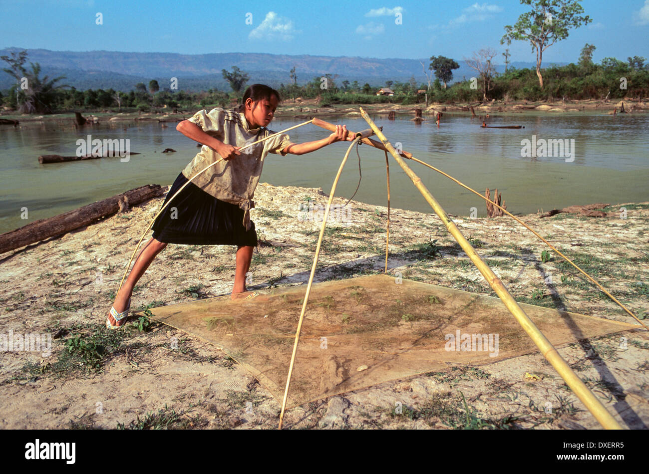 Laos uomo rete da pesca poli di bambù riverbank alberi sunshine fiume blu sabbia acqua cielo blu soffici nuvole Foto Stock