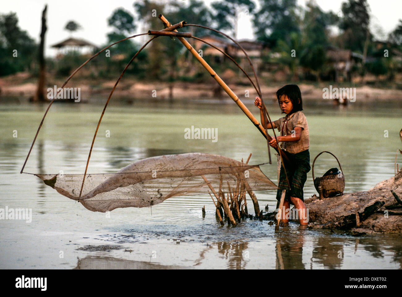 Laos bambini rete da pesca poli di bambù riverbank alberi sunshine fiume acqua blu Ragazzi Ragazze Foto Stock