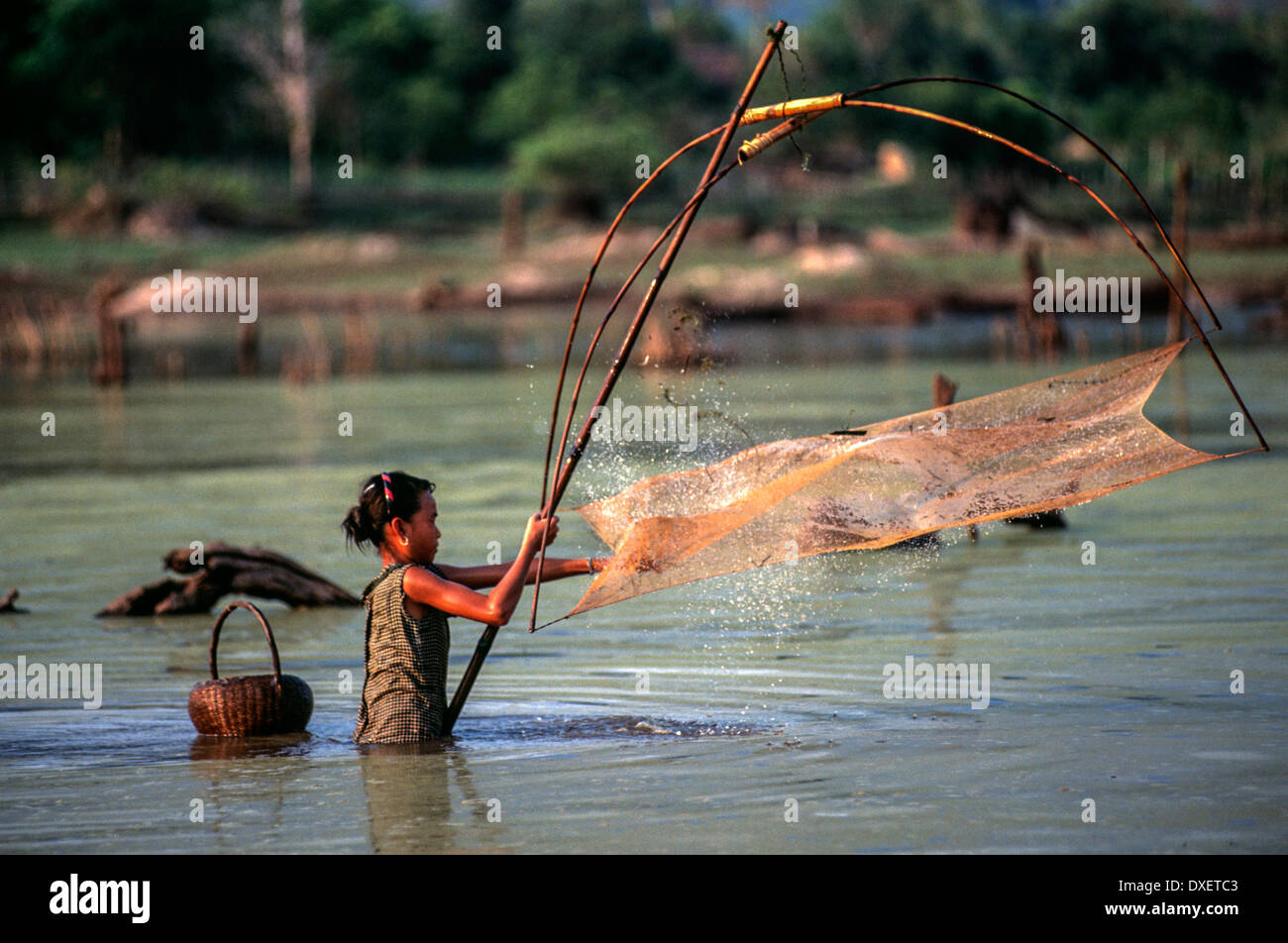 Laos donna rete da pesca poli di bambù cesto tessuto galleggianti blue sky riverbank soffici nuvole alberi sunshine fiume di acqua Foto Stock