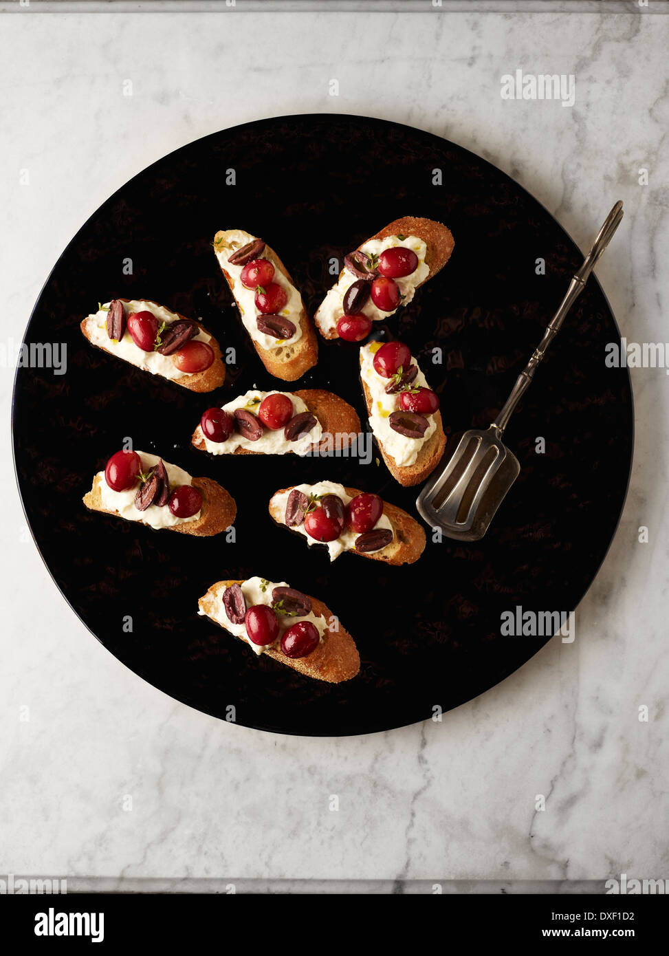Vista aerea di uva i crostini sul piatto di portata con le tenaglie, Studio Shot Foto Stock