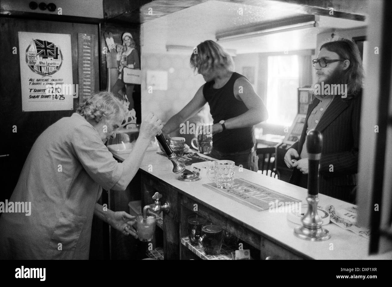 Pub interno, vita da villaggio dello Shropshire anni '1970. La padrona di casa, la signora Eliza Lewis, e i clienti al bar dell'All Nations Inn at Madeley, Telford, Shropshire Home-Brew pub, la padrona di casa che tirava una pinta con il suo camice. 1978 REGNO UNITO INGHILTERRA HOMER SYKES Foto Stock