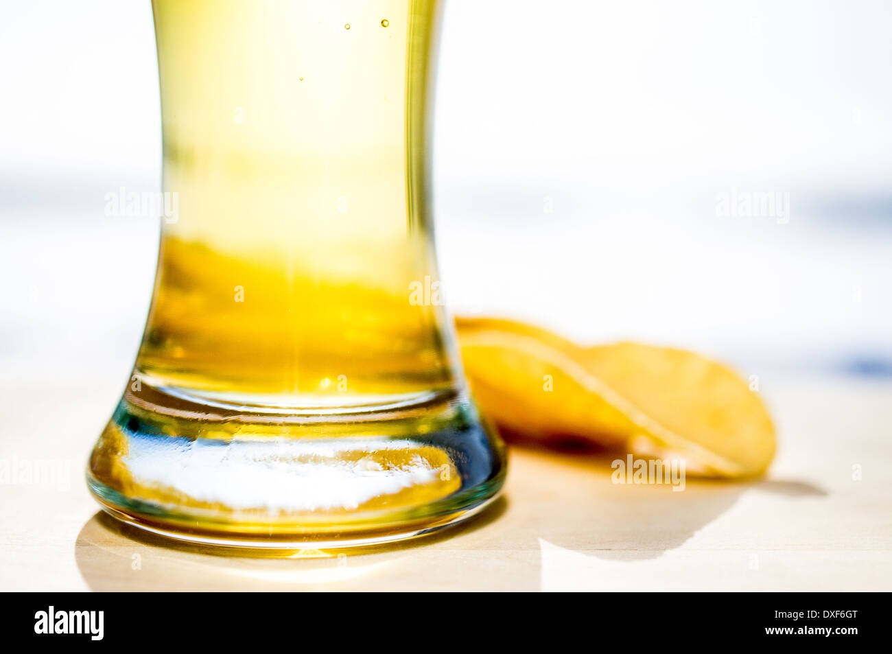 La pinta di birra. La formazione di schiuma di un bicchiere di birra e patatine in background. Foto Stock