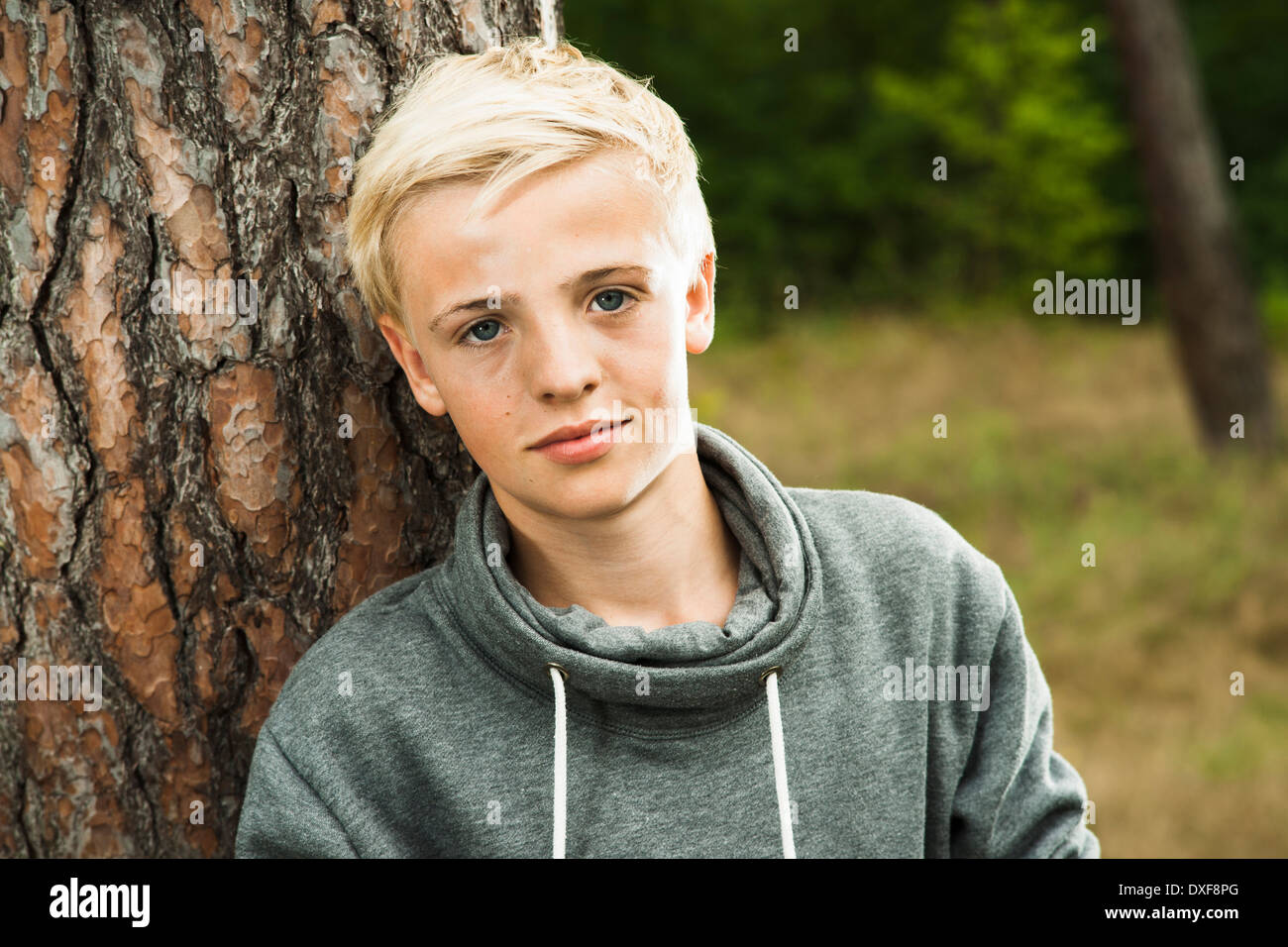 Close-up ritratto del ragazzo in piedi di fronte ad albero nel parco, guardando la telecamera, Germania Foto Stock