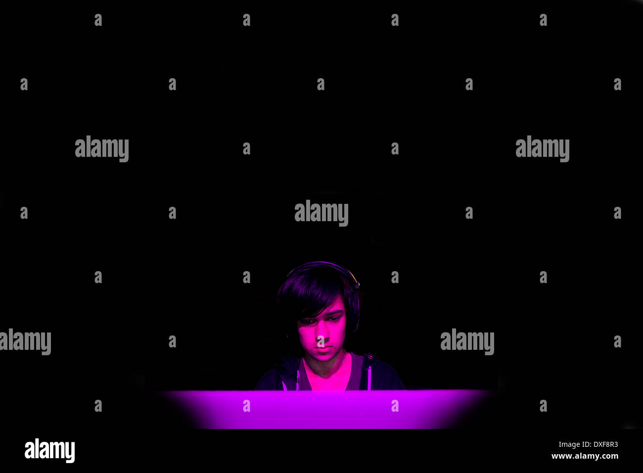 Un adolescente di sesso maschile giocando a un gioco per computer in una camera oscura. Foto Stock