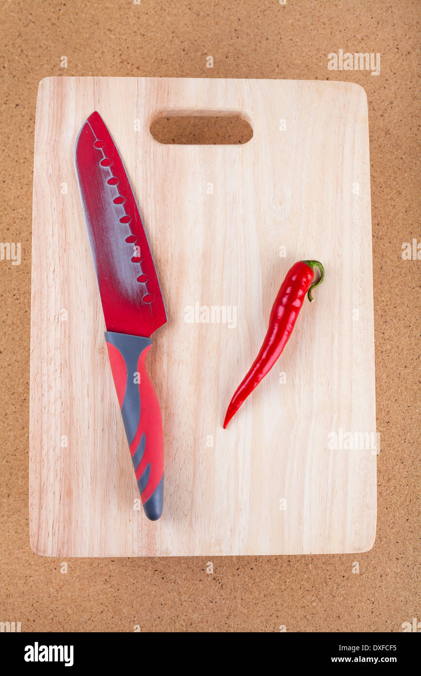 Fresh red hot chili pepper con il coltello sul tagliere. Foto Stock