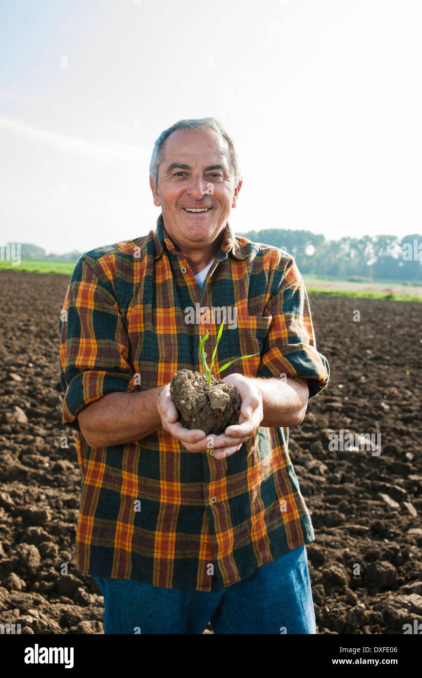 Ritratto di agricoltore in piedi in campo, azienda piantina pianta da coltura, Germania Foto Stock