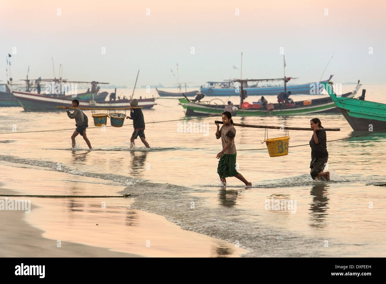 Popolo birmano portando nelle notti di catture da barche da pesca all'alba. Nei pressi del villaggio di pescatori sulla spiaggia di Ngapali in Myanmar. Foto Stock