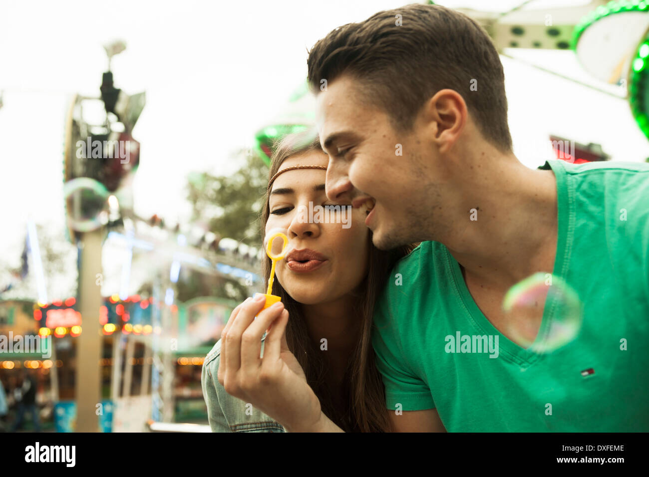 Close-up ritratto della coppia giovane soffiare bolle al parco di divertimenti, Germania Foto Stock