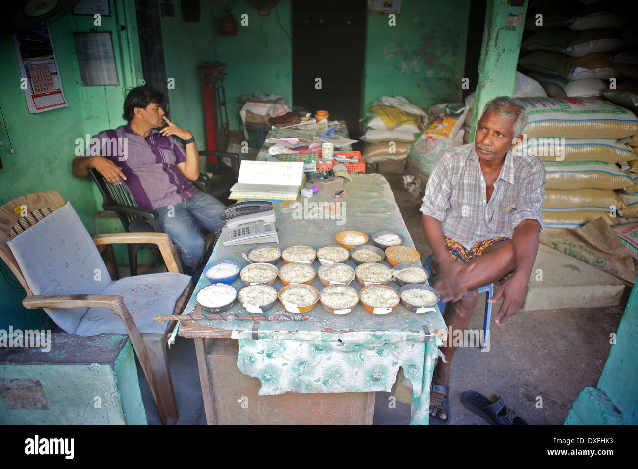 Gli uomini seduti in un magazzino che mostra campioni di riso Foto Stock