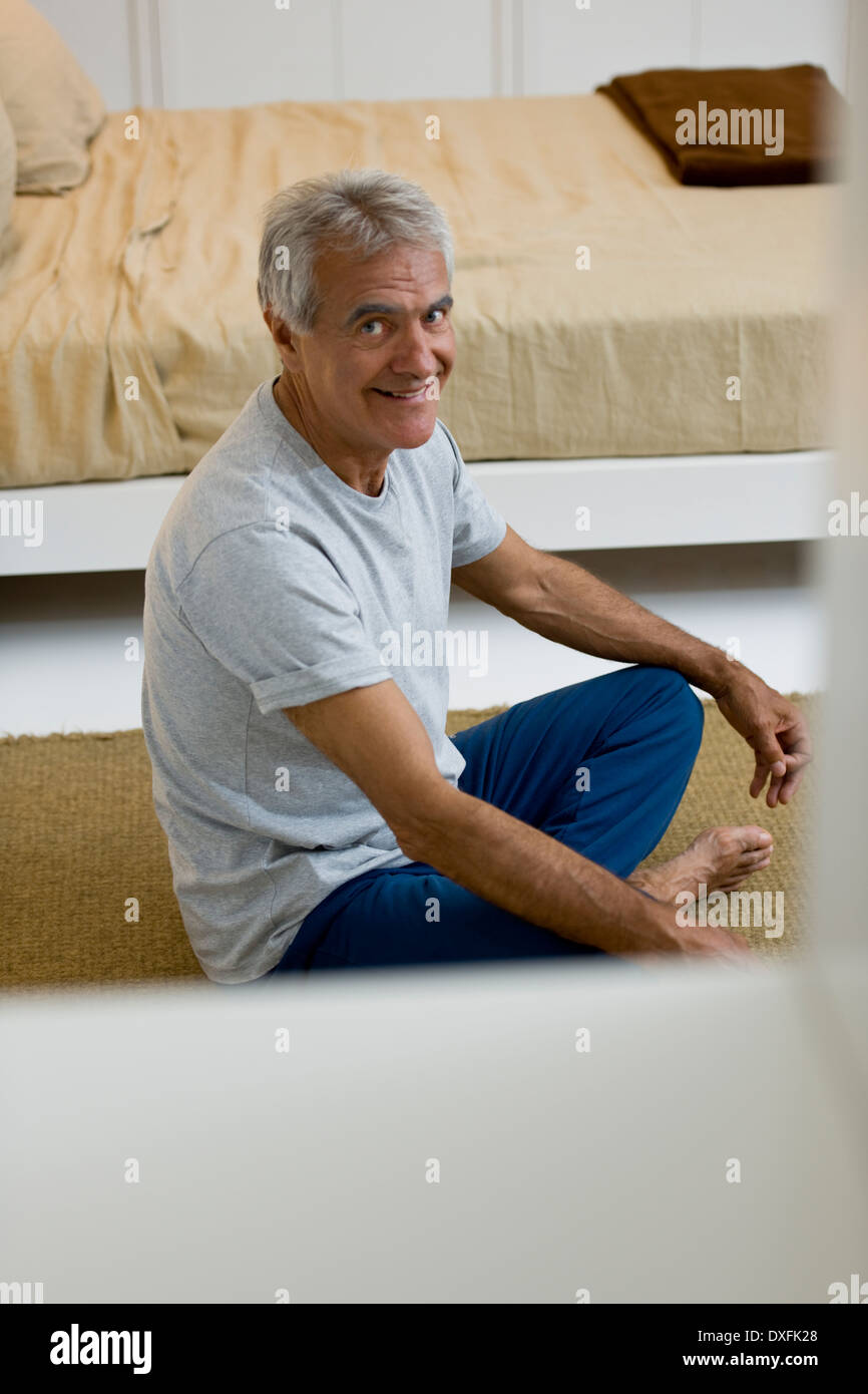 Uomo maturo fare yoga in camera da letto Foto Stock
