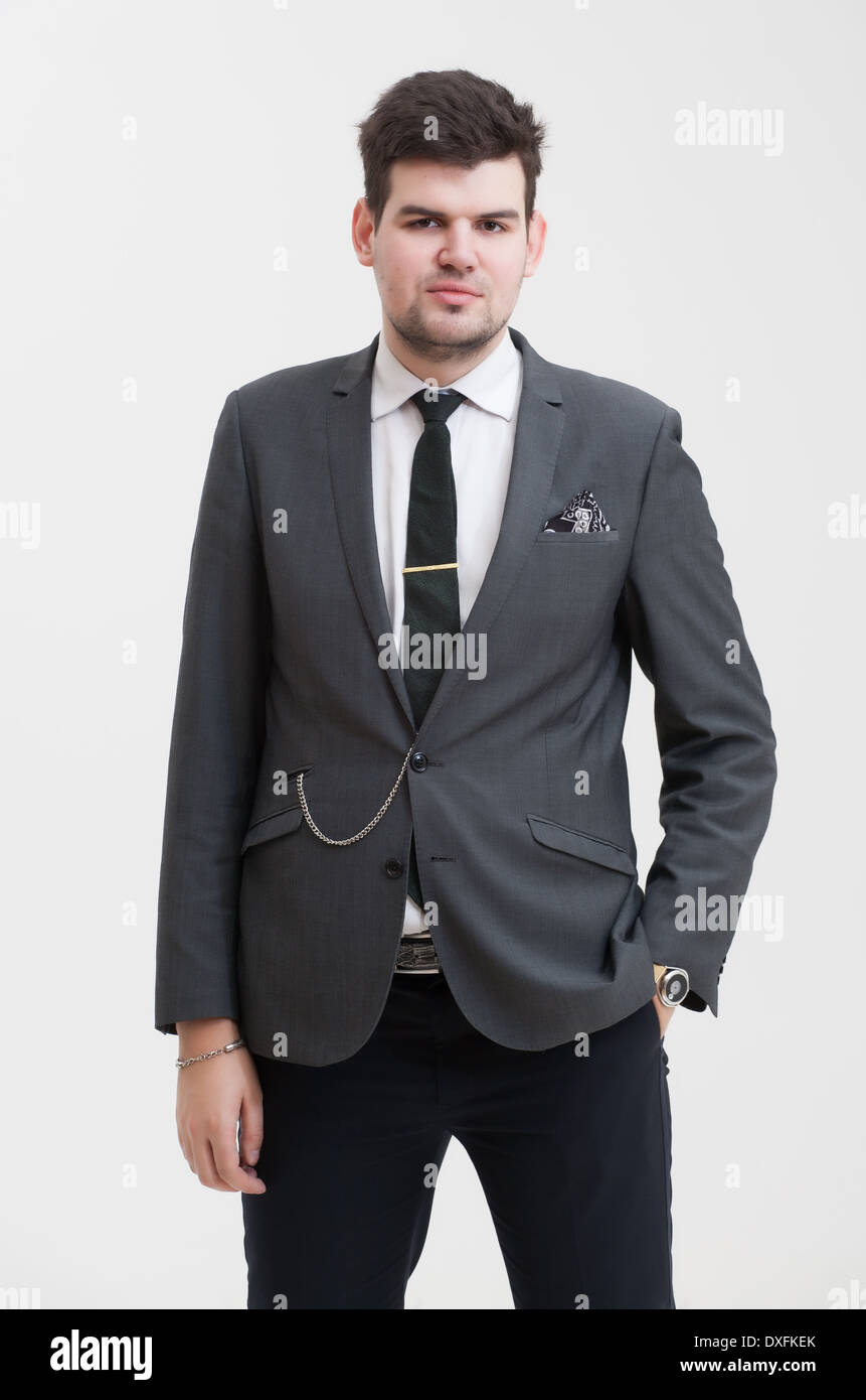 Ritratto di un bel giovane imprenditore nel bel grigio scuro tuta. Le sue mani in tasca dei pantaloni. Foto Stock