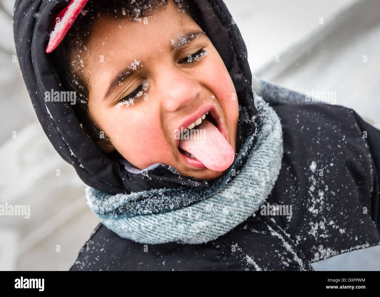 Giovane ragazzo giocando la cattura di fiocchi di neve sulla sua linguetta. Foto Stock