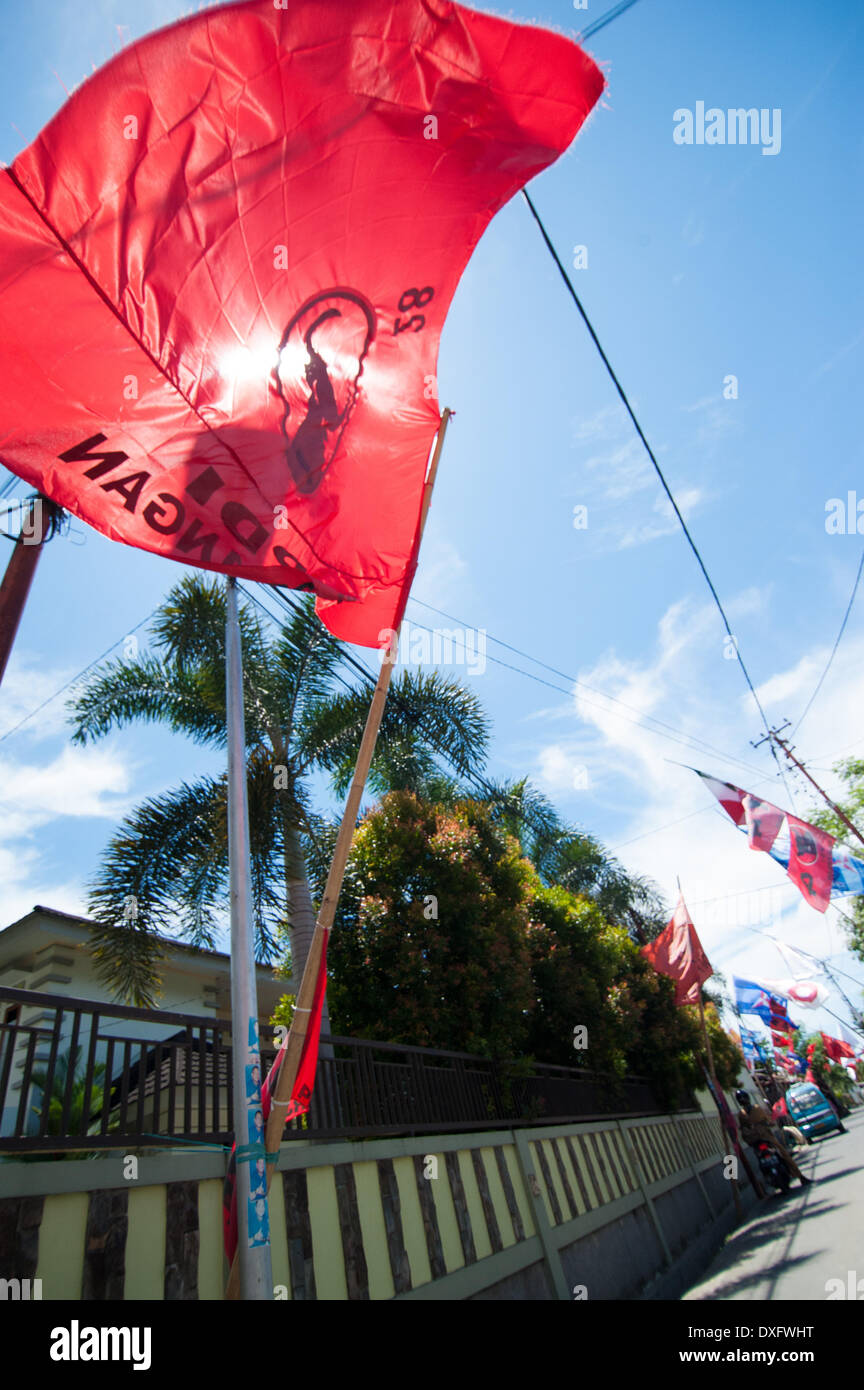 Manado, Nord Sulawesi, Indonesia. Il 26 marzo 2014. Le bandiere e gli striscioni pubblicità del popolo simpatie politiche verso il basso una strada residenziale a Manado nel Nord Sulawesi. Il legislative indonesiane elettorale per eleggere i membri di entrambe le nazionali e regionali di legislature avrà luogo il 9 aprile 2014 la bandiera rossa per il Partai Demokrasi Indonesia Perjuangan, popolare a Manado in credito: Andrew Walmsley/Alamy Live News Foto Stock