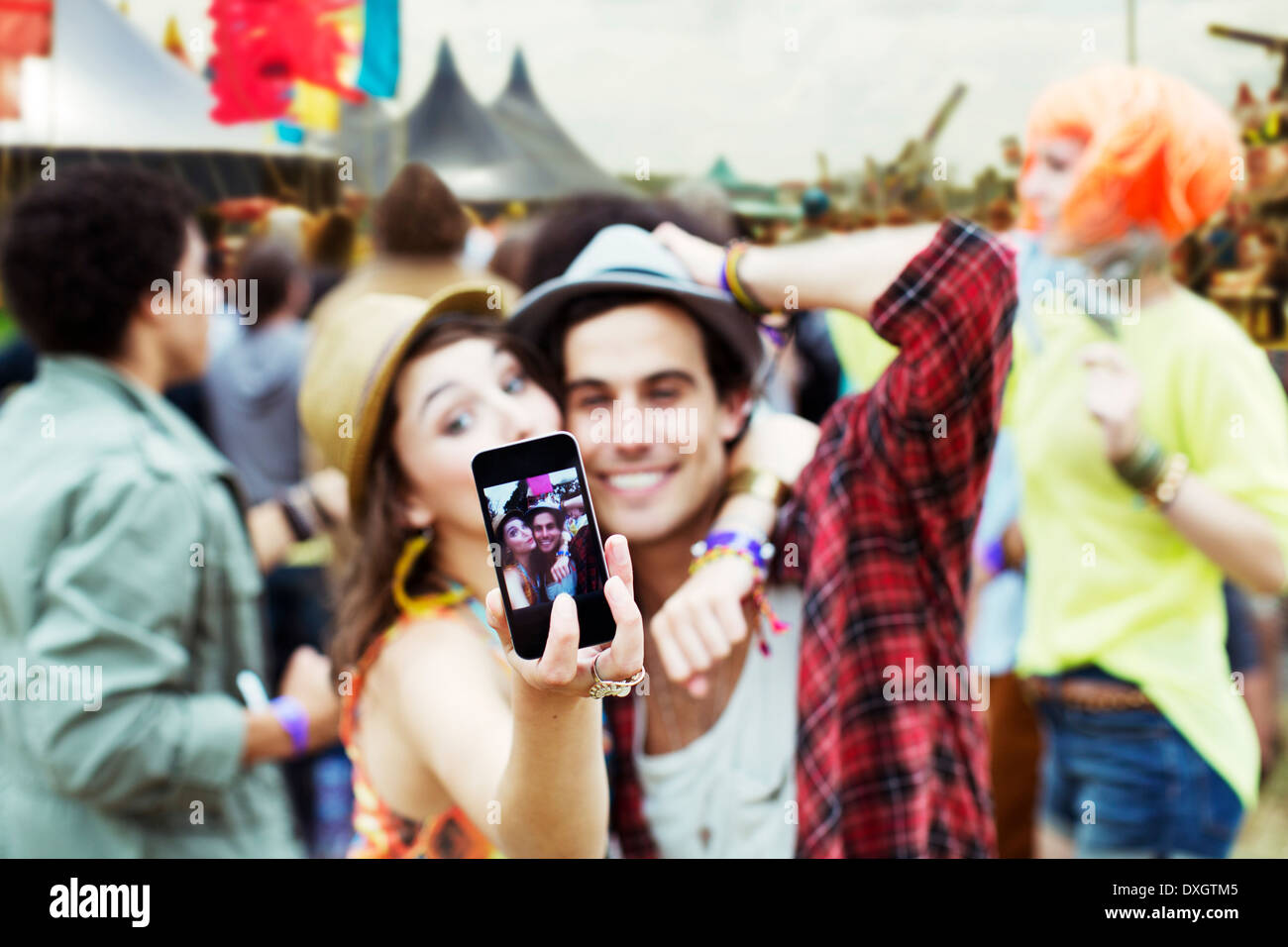 Giovane tenendo autoritratto con telefono con fotocamera al festival di musica Foto Stock