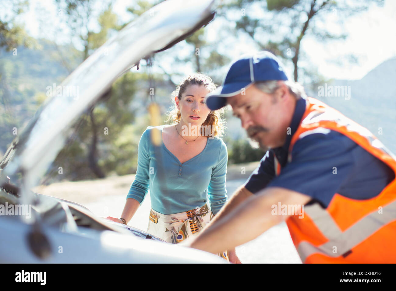 La donna guarda la strada controllo meccanico auto a motore Foto Stock