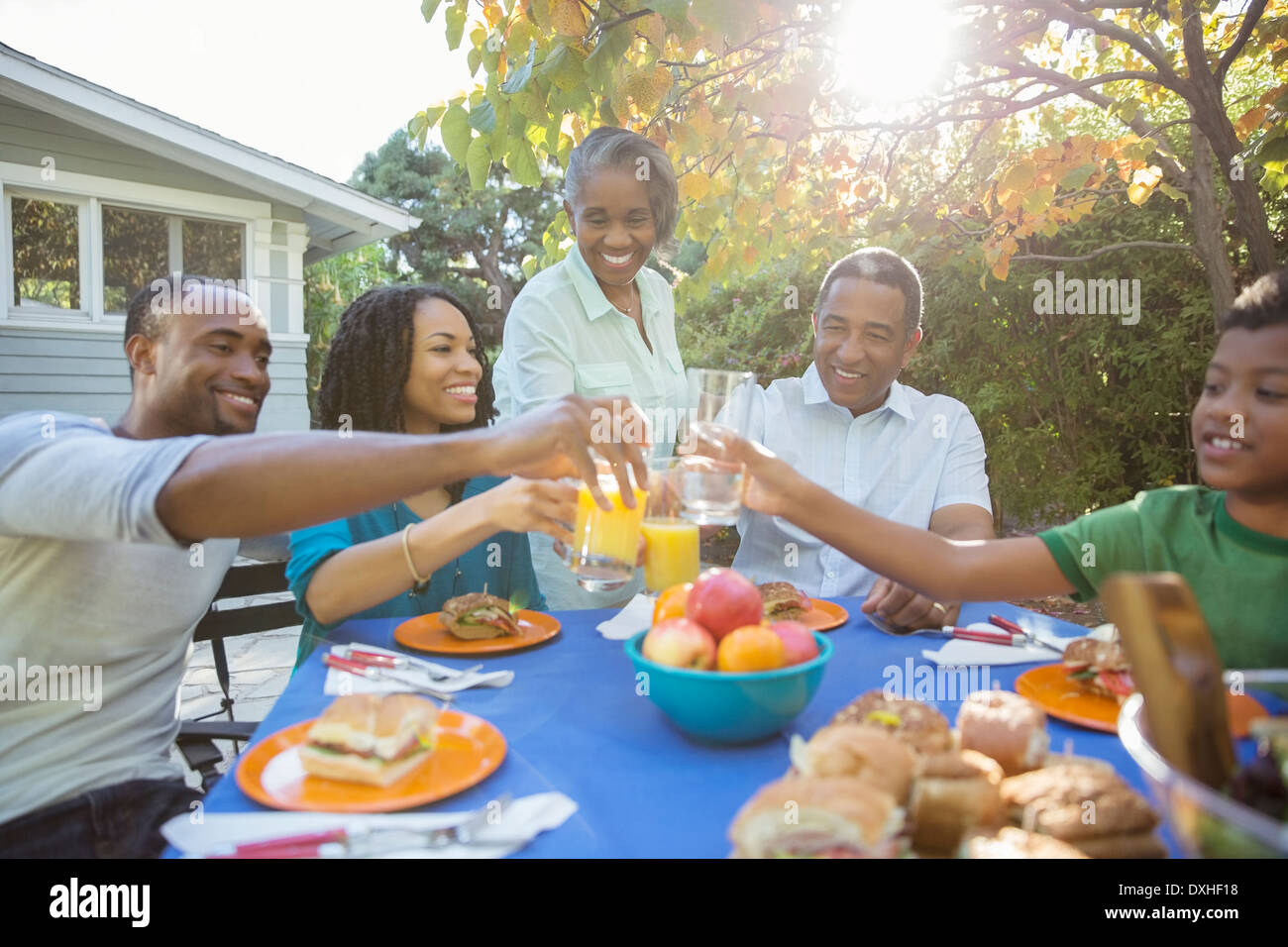 La famiglia felice di tostatura bicchieri di succo al patio tabella Foto Stock