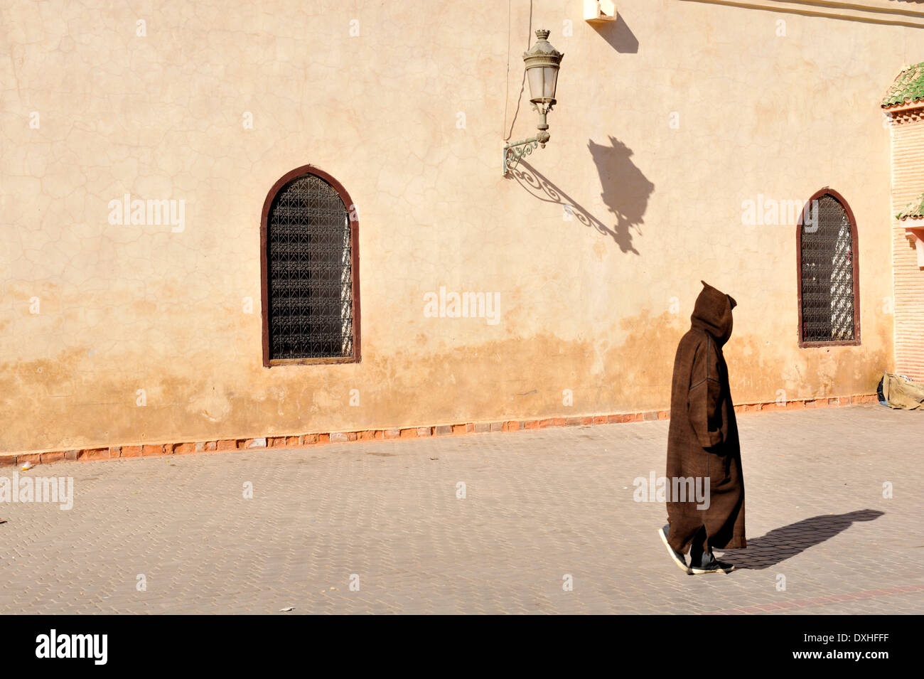 Berber, marocchini, uomo nel tradizionale accappatoio con cappuccio a piedi dalla parete, Marrakech, Marocco Foto Stock