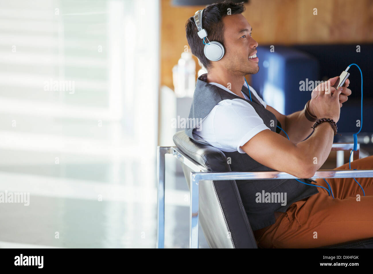 Imprenditore sorridente ascolto di musica sul lettore mp3 con cuffie Foto Stock