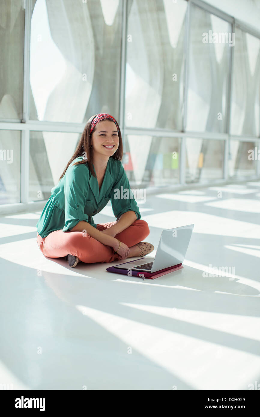 Ritratto di fiducioso casual imprenditrice utilizzando laptop sul pavimento in sole ufficio Foto Stock