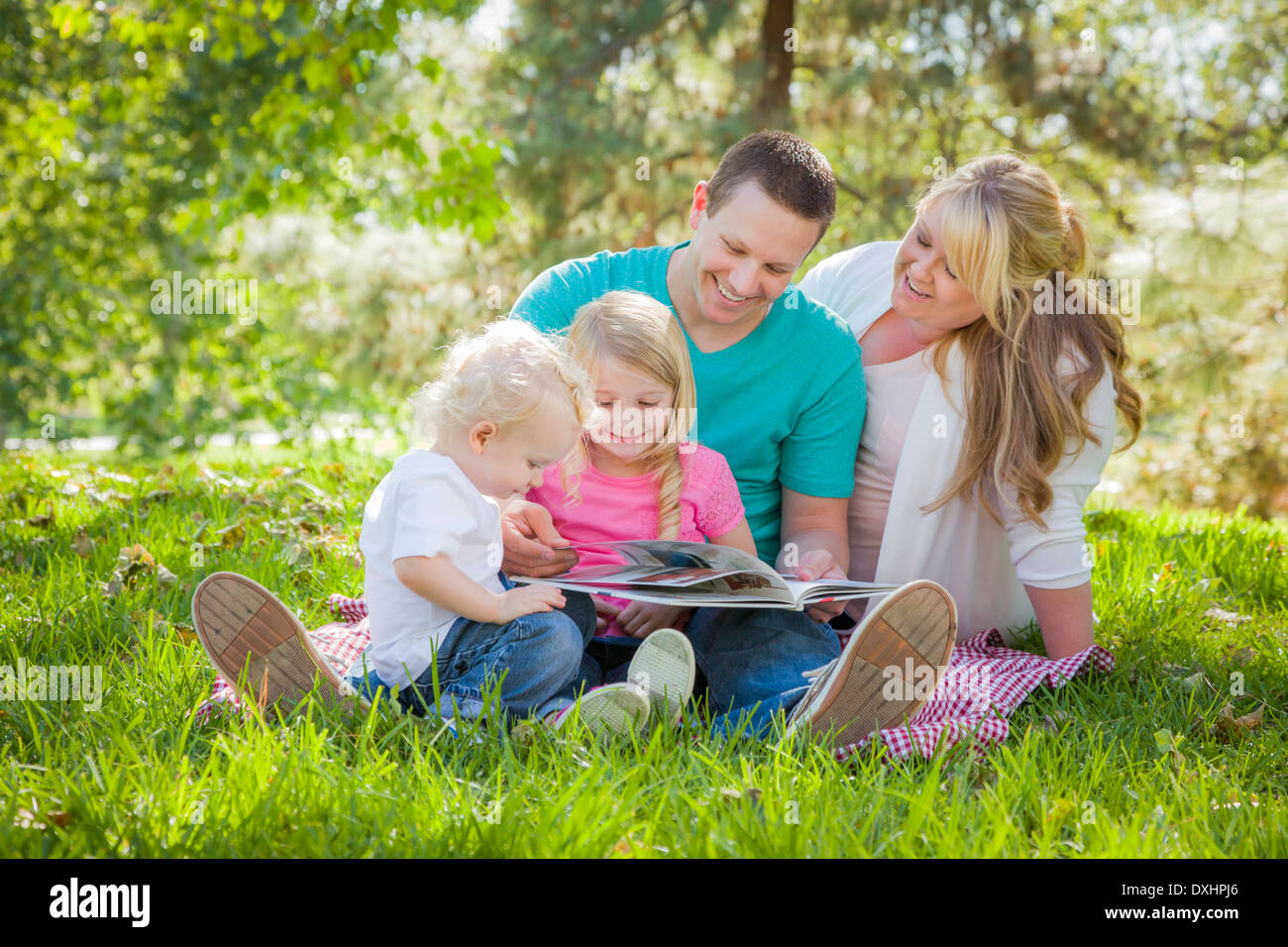 Famiglia giovane gode di lettura di un libro insieme nel parco. Foto Stock