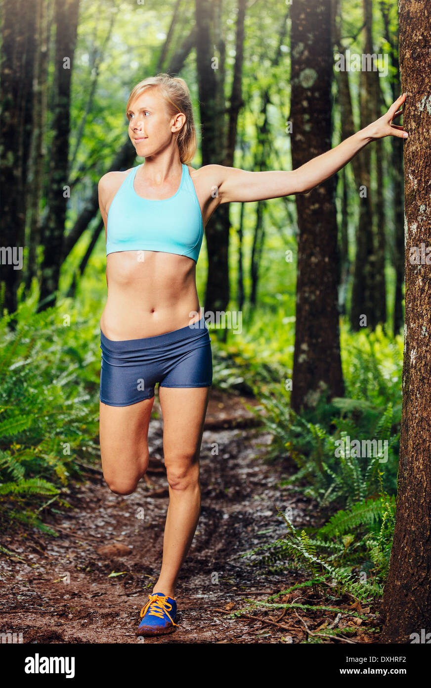 Athletic donna stretching prima di andare per correre nella foresta. Attiva uno stile di vita sano concetto. Foto Stock