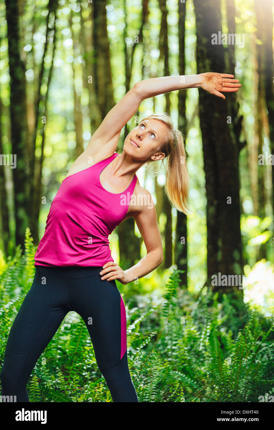 Athletic donna stretching prima di andare per correre nella foresta. Attiva uno stile di vita sano concetto. Foto Stock