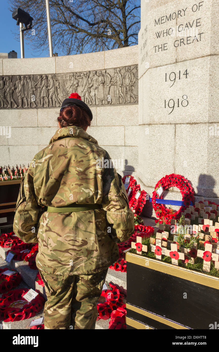 Una giovane donna in army fatigues in piedi dai Memoriali di papavero presso la War Memorial, Bury, Lancashire sul ricordo domenica 2013 Foto Stock