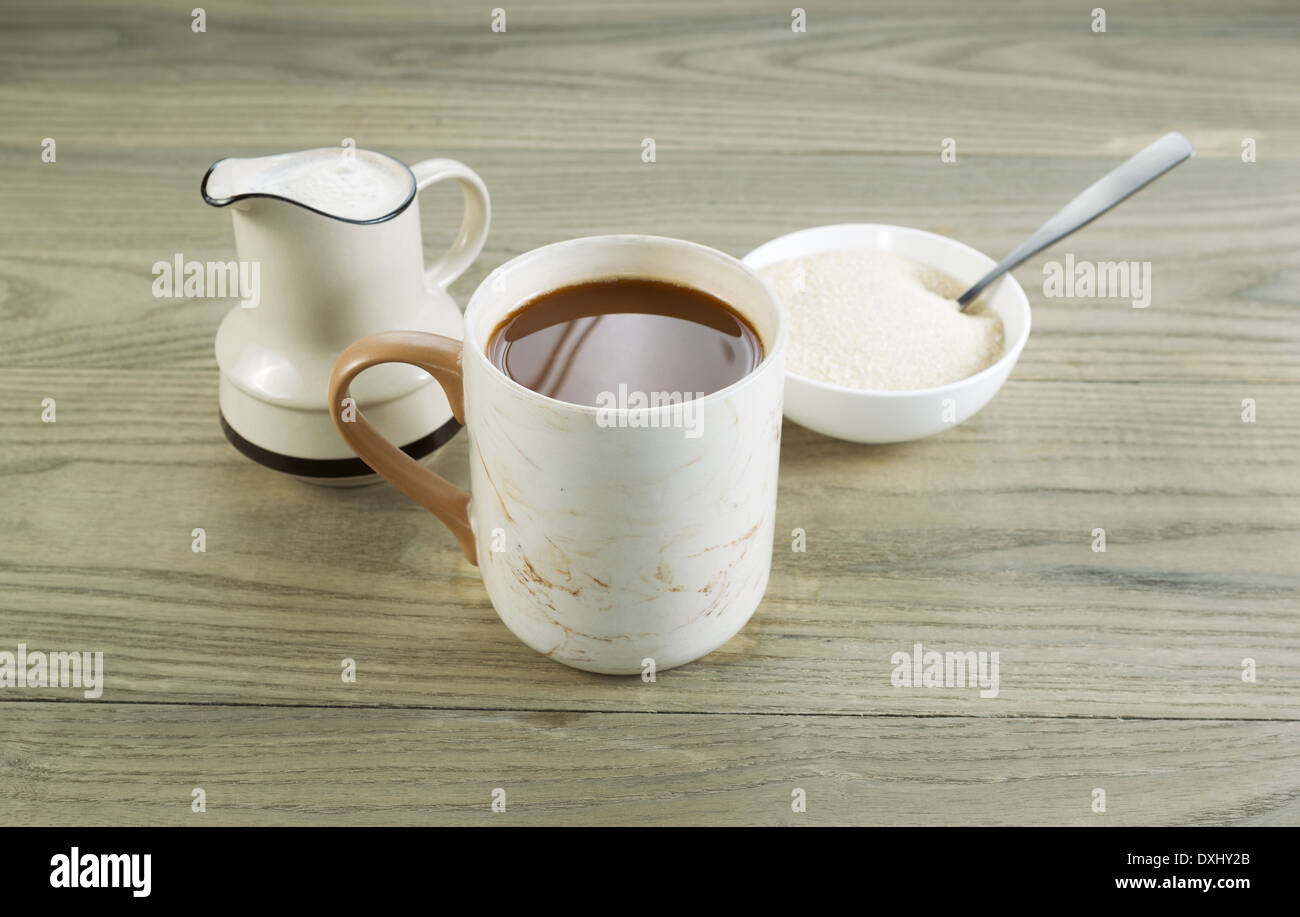 Closeup foto orizzontale di una tazza piena di caffè con lo zucchero e il cucchiaio nella ciotola e crema nel beccuccio versatore con legno invecchiato Foto Stock