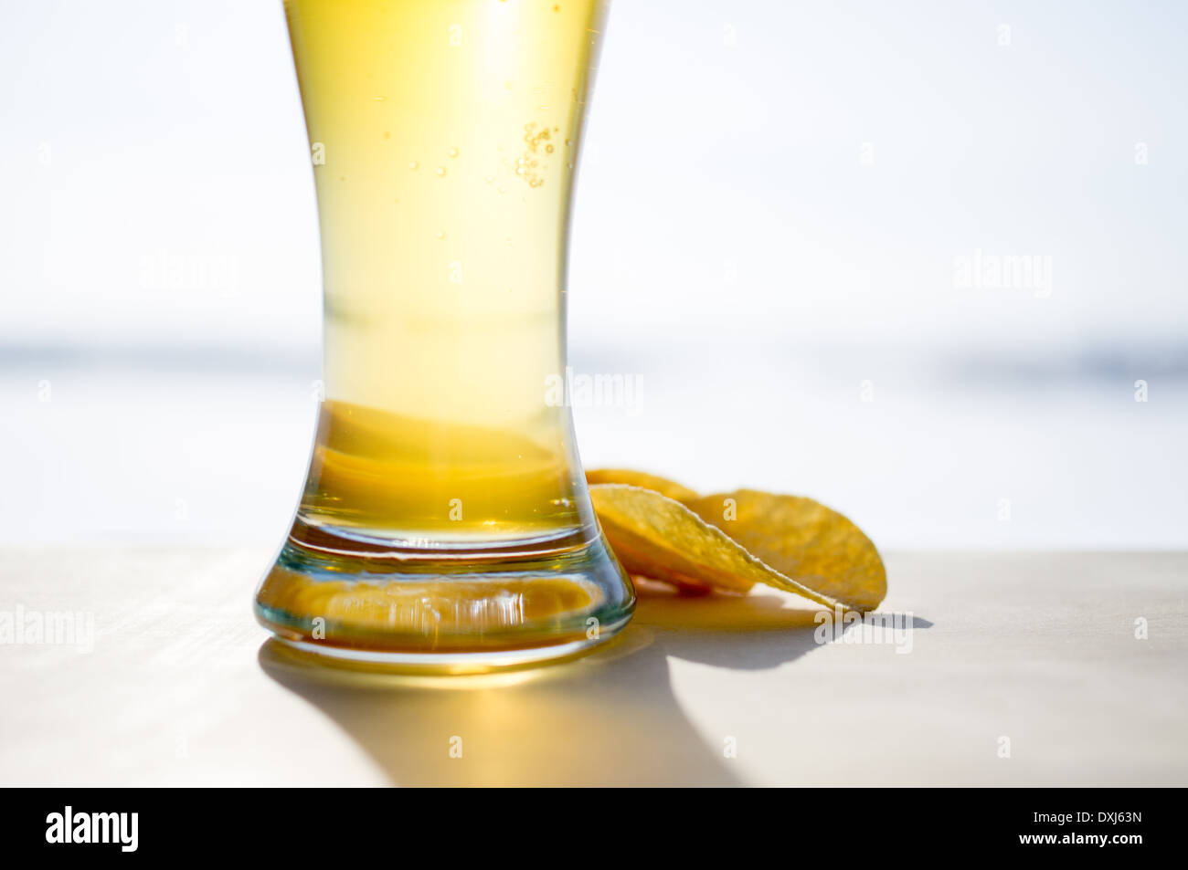 La formazione di schiuma di un bicchiere di birra e patatine in background. La pinta di birra Foto Stock