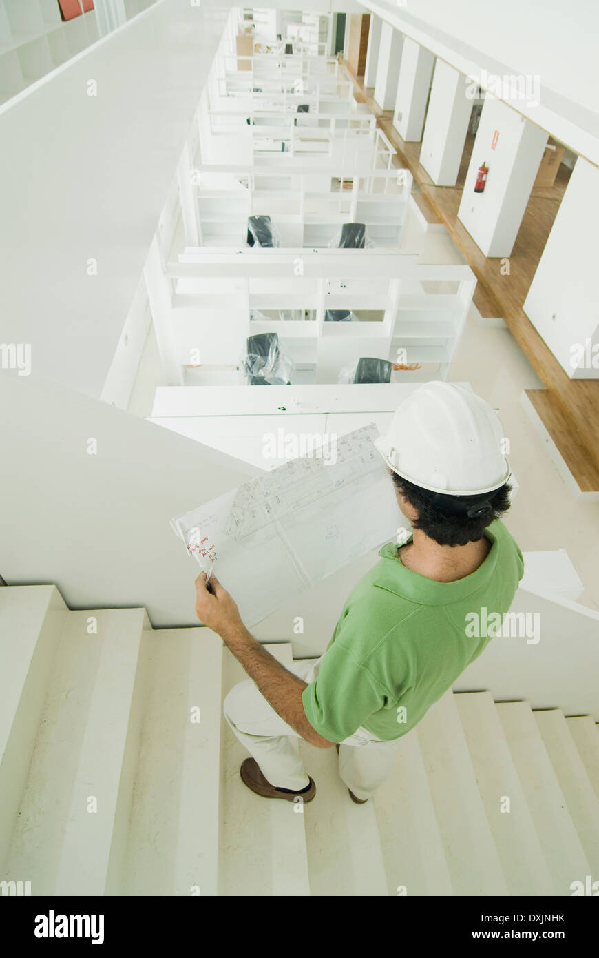 Uomo che indossa elmetto in piedi nel nuovo ufficio di piani di contenimento Foto Stock