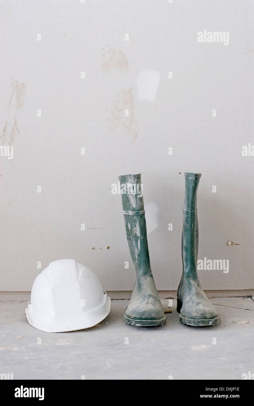 Coppia di sporco stivali da lavoro e bianco elmetto Foto Stock