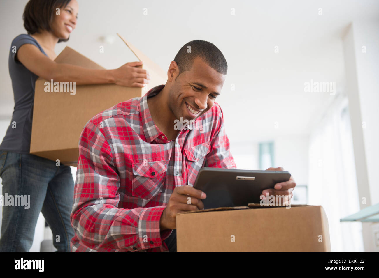 Coppia con tavoletta digitale e contenitori per il trasloco Foto Stock