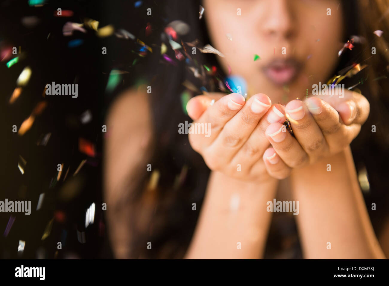 Close up della donna asiatica soffiando confetti di mani Foto Stock