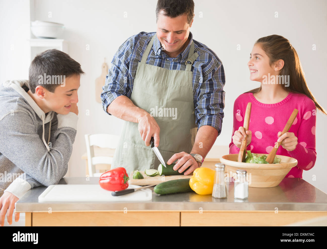 Padre caucasica e bambini la preparazione di insalata in cucina Foto Stock