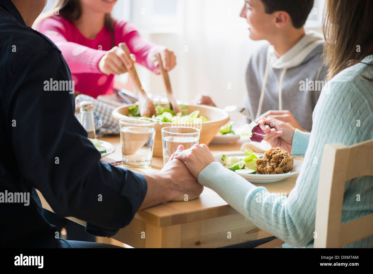 I genitori caucasici tenendo le mani sul tavolo Foto Stock