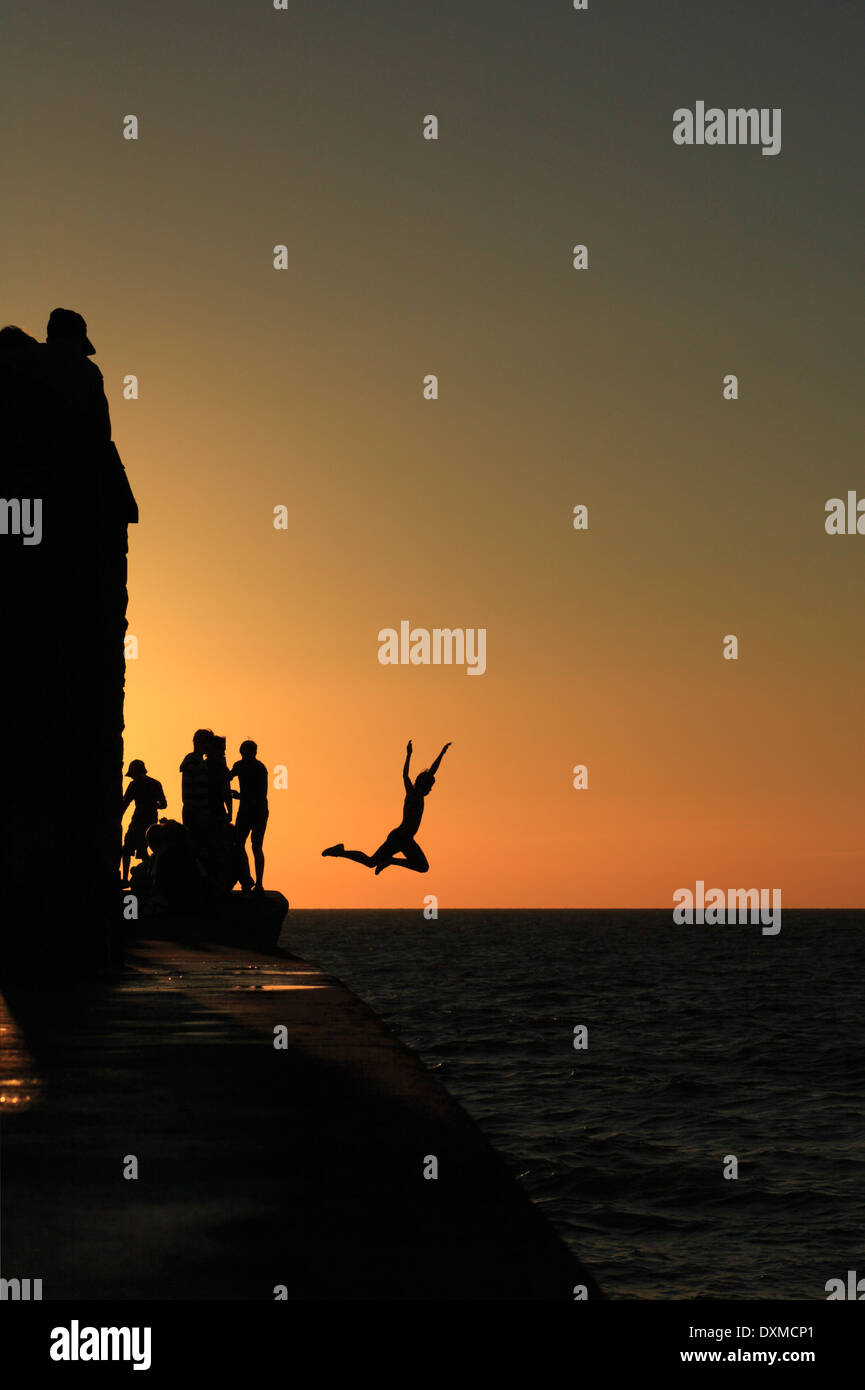 Un gruppo di giovani si alternano con un tuffo nel mare di Aberaeron in Galles. Foto Stock