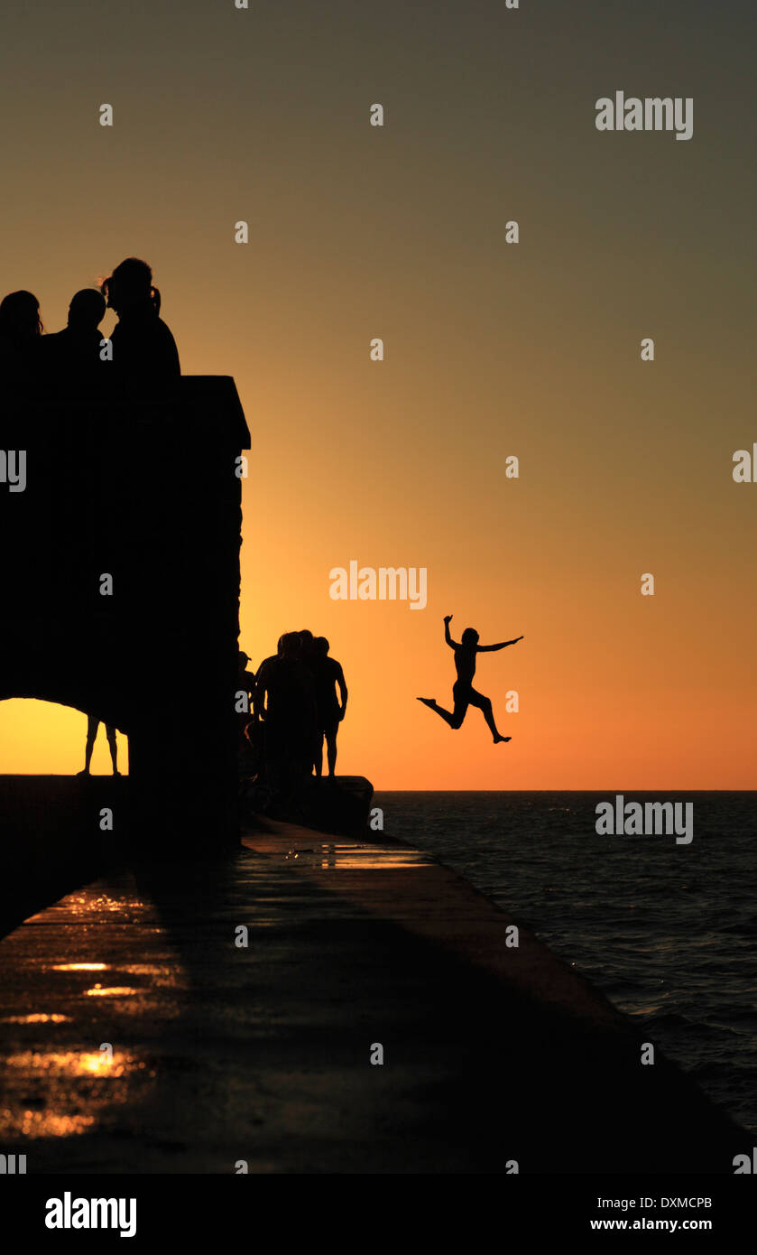 Un gruppo di giovani si alternano con un tuffo nel mare di Aberaeron in Galles. Foto Stock