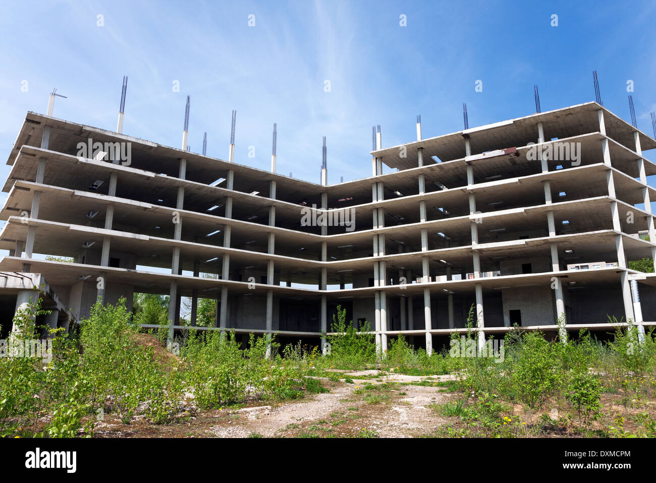 Abbandonato sito in costruzione ricoperta da erba su soleggiate giornate estive Foto Stock