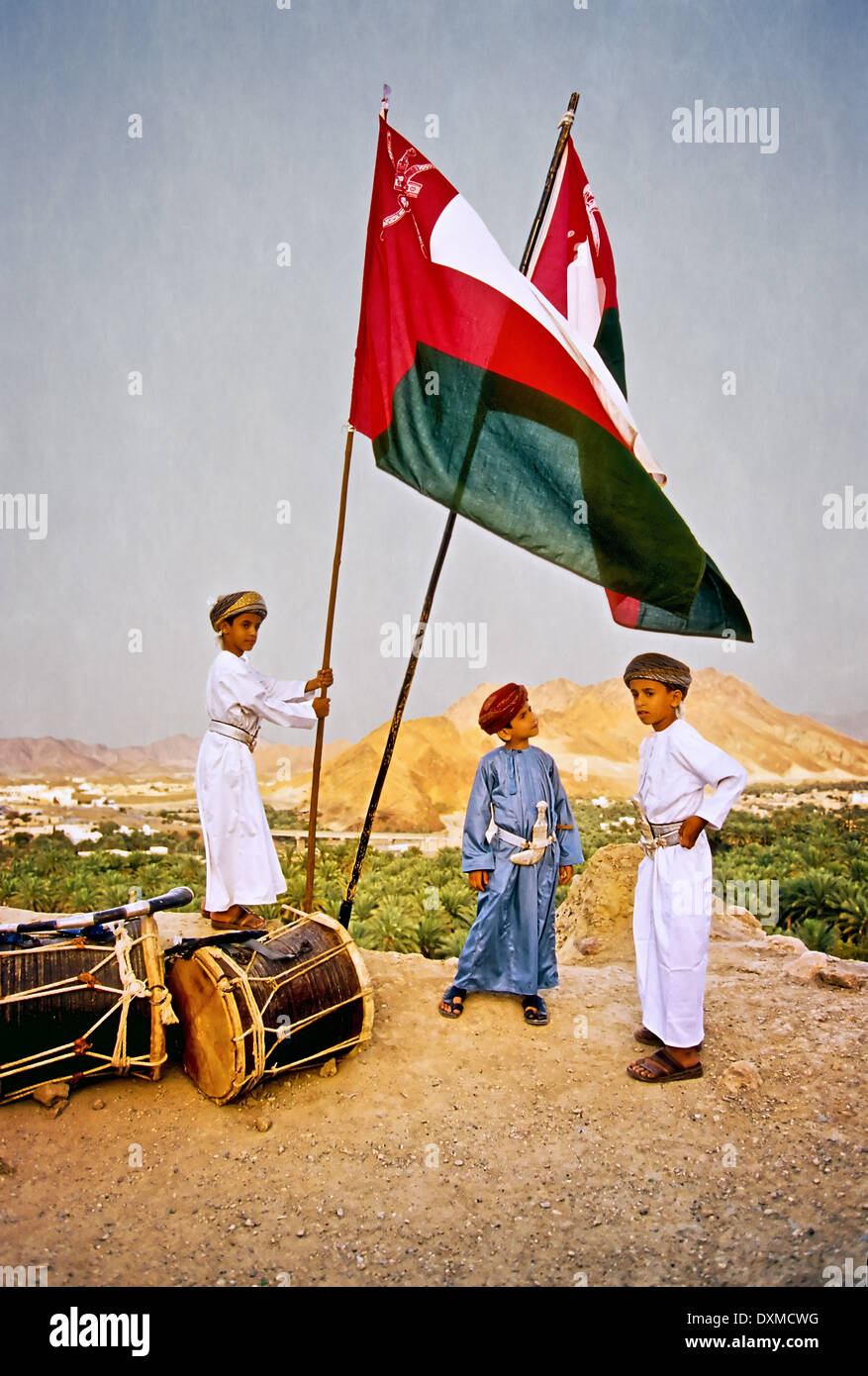 I bambini in abito tradizionale e la bandiera dell'Oman all'Eid al-fitr celebrazione in Fanja, Oman. Manipolati digitalmente immagine. Foto Stock