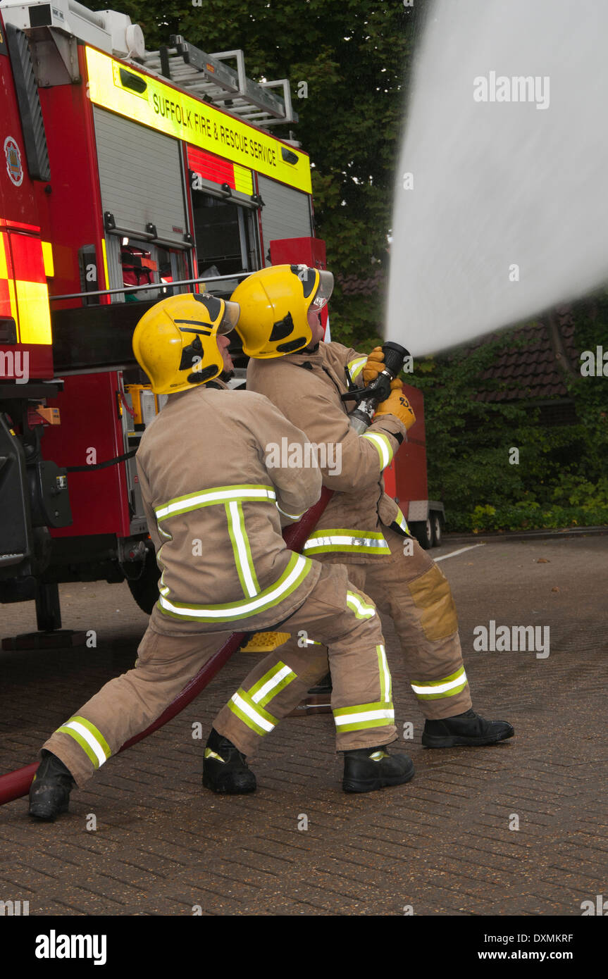 Due vigili del fuoco dimostrando fuoco tecnica del tubo flessibile Foto Stock