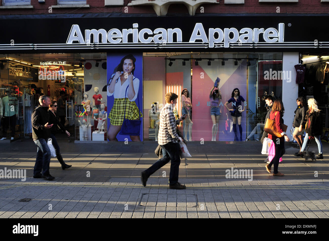 La gente a piedi passato American Apparel shop in Oxford Street, London, Regno Unito Foto Stock