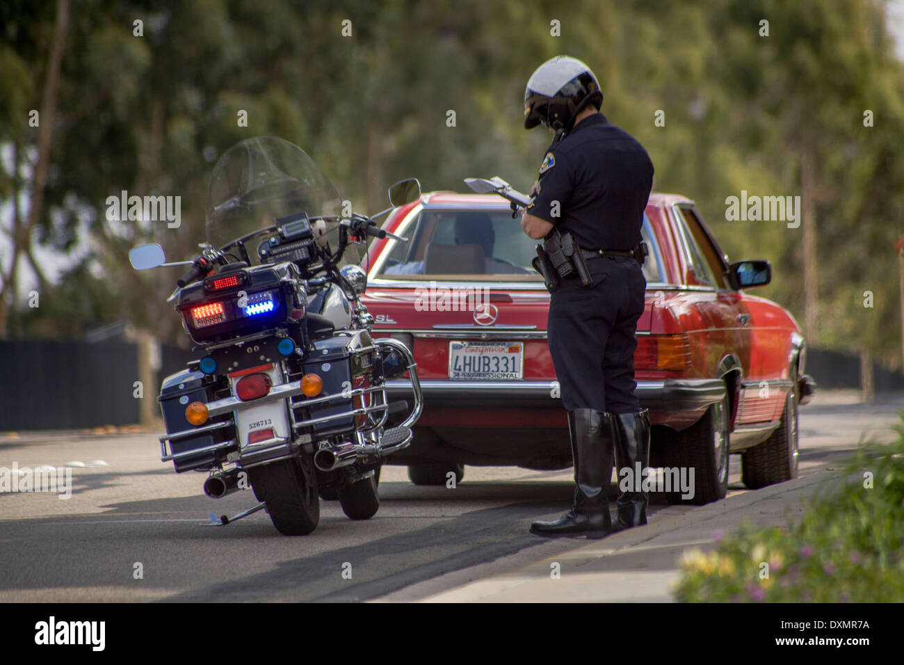 Un motociclo poliziotto scrive un biglietto a un arresto del traffico in arancione, CA. Foto Stock