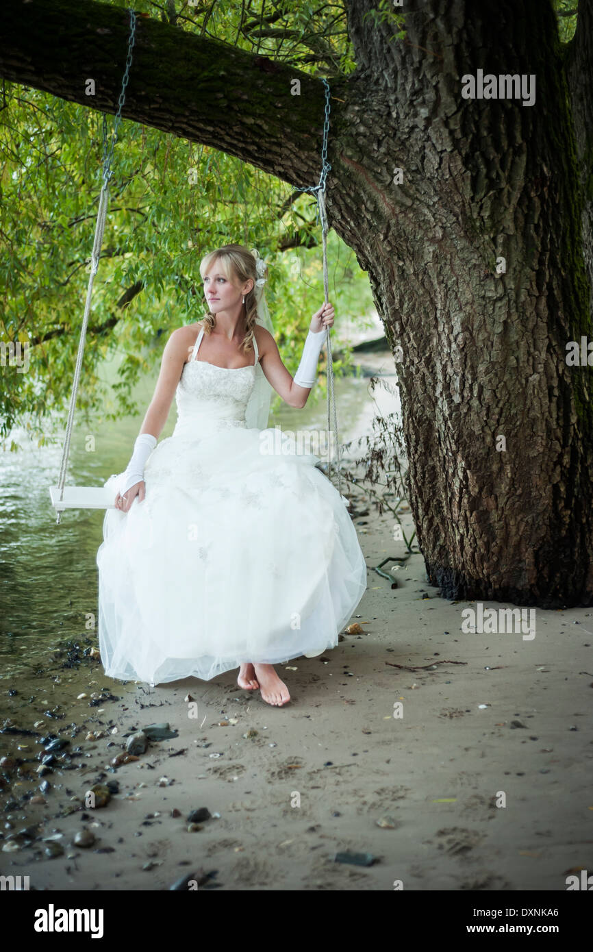 In Germania, in Renania Palatinato, ritratto di sposa seduto su una oscillazione a riva del fiume Reno Foto Stock