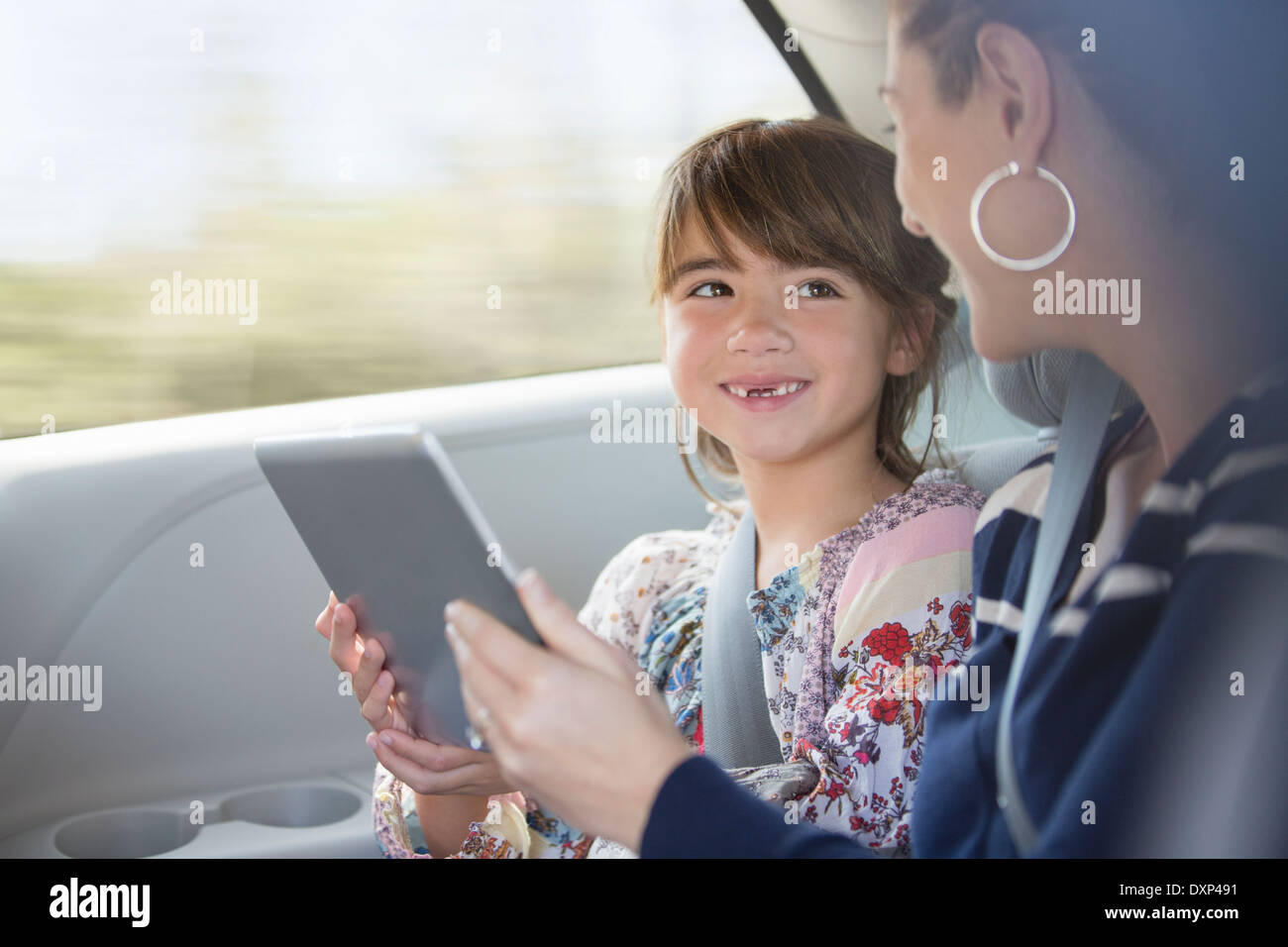 Felice madre e figlia utilizzando digitale compressa nel sedile posteriore della macchina Foto Stock