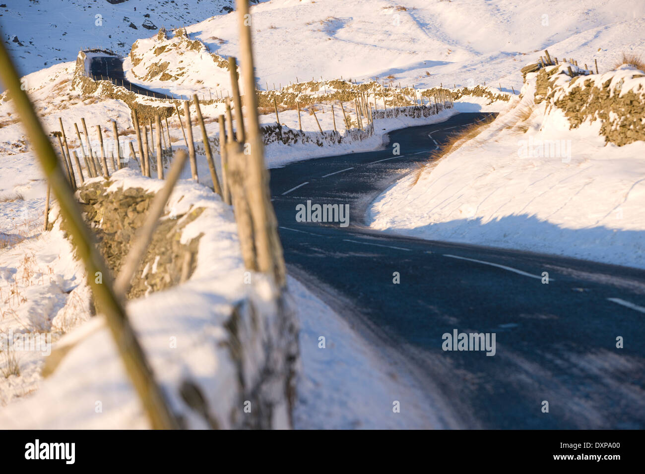 La torsione strada di montagna sopra il Kirkstone Pass in snow Lake District Inghilterra Foto Stock