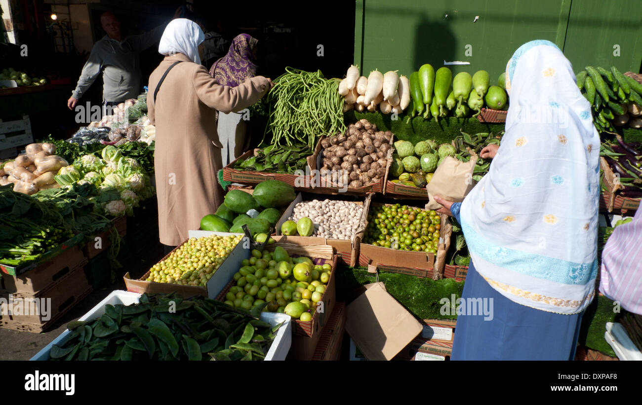 Le donne musulmane shopping alimentare acquistare frutta e verdura presso un negozio di stallo in Whitechapel High Street Market East London, England Regno Unito KATHY DEWITT Foto Stock